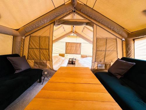 ein Holztisch in einem Zelt mit zwei Sofas in der Unterkunft Rasta Camp Hakushu - Vacation STAY 03221v in Shirasu