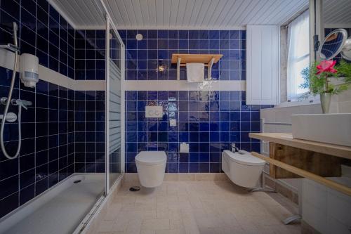 a blue tiled bathroom with a toilet and a shower at Casas da Tia Alice - Casas de campo encantadoras em Mafra in Mafra