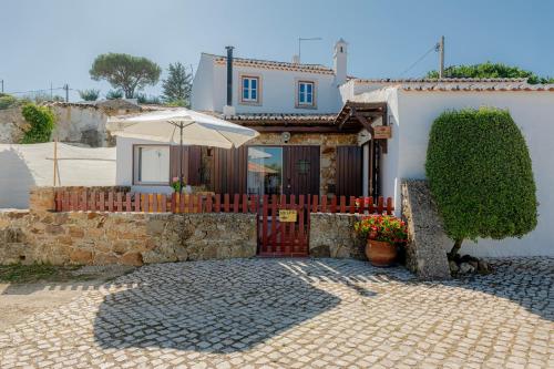 a house with an umbrella in front of it at Casas da Tia Alice - Casas de campo encantadoras em Mafra in Mafra