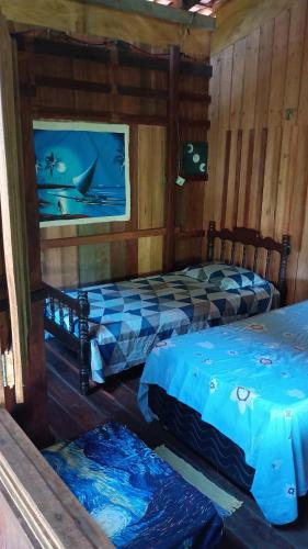 a bedroom with two beds and a painting on the wall at Hostel Dona Helô in Maracanã