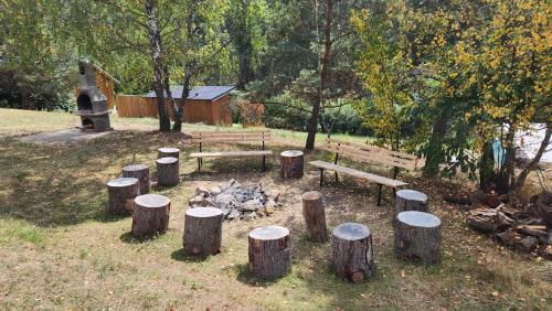 a park with benches and a fire and logs at Baribouda - Chaty Na Rybárně in Louka