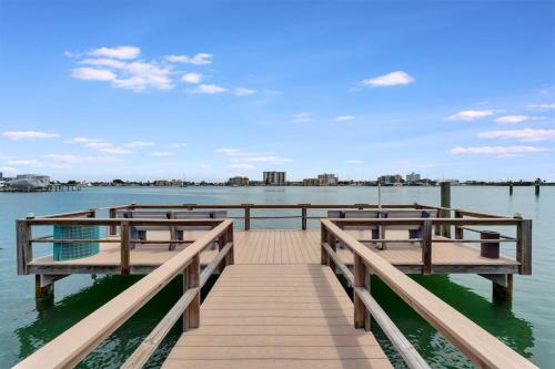 een dok met twee banken op het water bij Watch the dolphins Waterview 2-bed Heated pool in Clearwater Beach