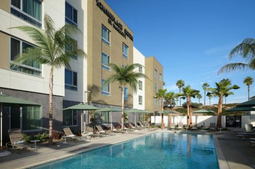 a pool at a hotel with chairs and palm trees at TownePlace Suites by Marriott Ventura Oxnard in Oxnard