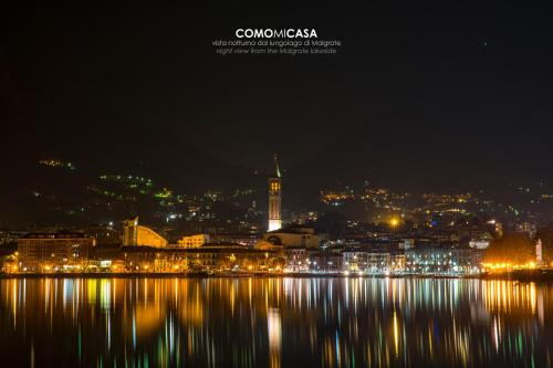 a city lit up at night with the water at COMO mi CASA in Malgrate