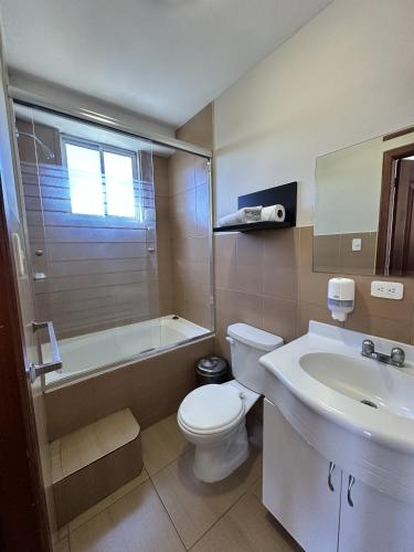 a bathroom with a toilet and a tub and a sink at Hotel Versailles in Ambato