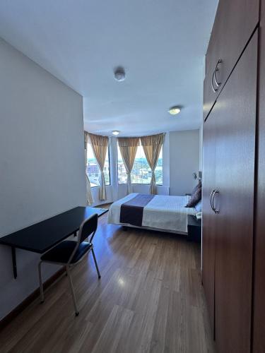 a bedroom with a bed and a desk and window at Hotel Versailles in Ambato