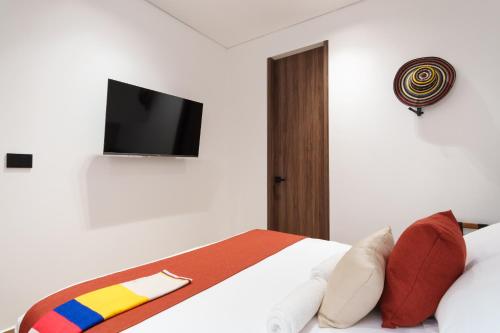a bedroom with a bed with a tv on the wall at Hotel CASA TAMA in Salento