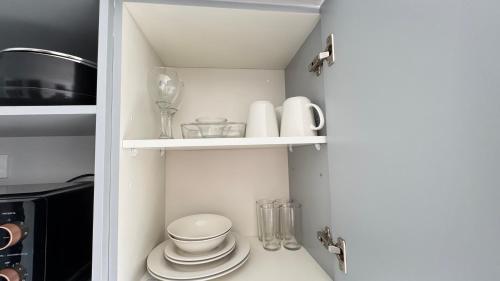 eine Speisekammer mit Tellern und Gläsern und einer Mikrowelle in der Unterkunft Movistar Arena, Parq OHiggins Estacionamiento Gratis in Santiago