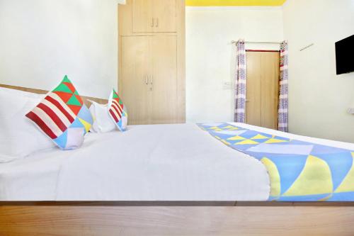 a bedroom with a large white bed with colorful pillows at HOME 78802 Balaji Bhawan Jhajra in Dehradun