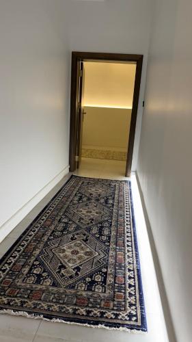 a hallway with an open door with a rug on the floor at نزل الجادية in Al Baha