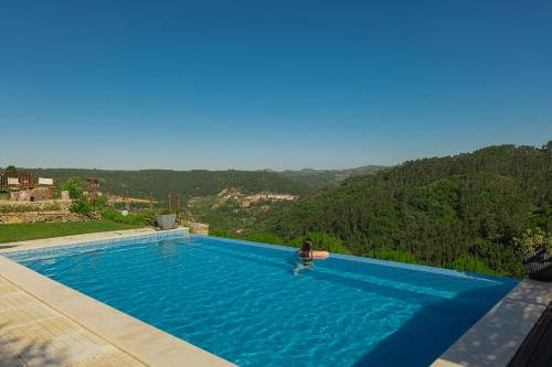 a person sitting on a chair in a swimming pool at Casas da Tia Alice - Casas de campo encantadoras em Mafra in Mafra