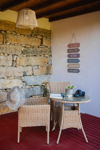 a table and chairs in a room with a stone wall at Casas da Tia Alice - Casas de campo encantadoras em Mafra in Mafra