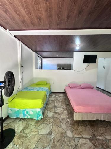 two beds sitting in a room with a fan at Vacaciones en Tortuguero in Tortuguero