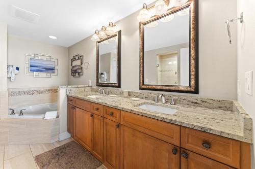 ein Badezimmer mit zwei Waschbecken, einer Badewanne und einem großen Spiegel in der Unterkunft Azure 501 - Beachfront Luxury & Stunning Ocean Views! in Fort Walton Beach