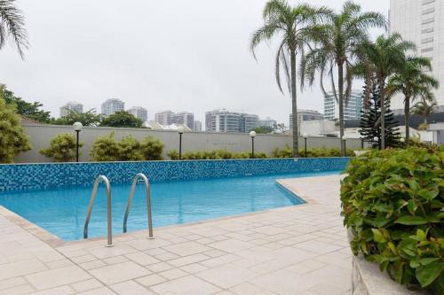 a swimming pool with palm trees and a building at Flat Praia, Piscina e Sauna - Frente Mar - D68104 in Rio de Janeiro
