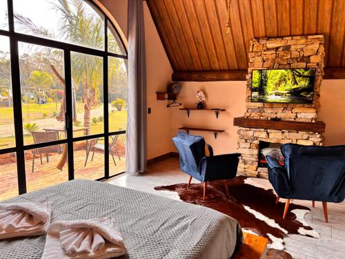 a bedroom with a fireplace and two chairs and a bed at Recanto da Natureza in Brotas