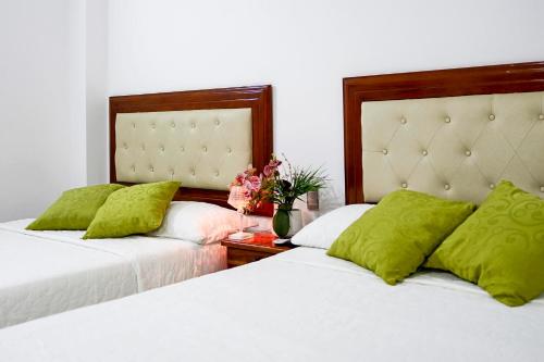 two beds with green pillows in a bedroom at Posada Sueño Real in San Martín