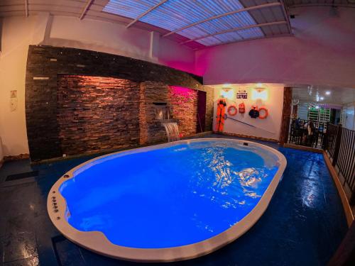 a large blue pool in a room with a brick wall at Posada Sueño Real in San Martín