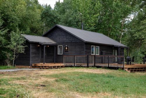 a black cabin with a fence in front of it at Black Bear Bungalow w/Hot Tub! in Gallatin Gateway