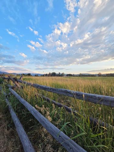 a wooden fence in a field with a cloudy sky at Black Bear Bungalow w/Hot Tub! in Gallatin Gateway