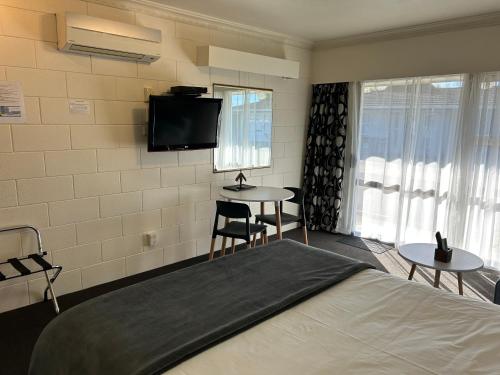 a bedroom with a bed and two tables and a tv at Montana Lodge Motel in Blenheim