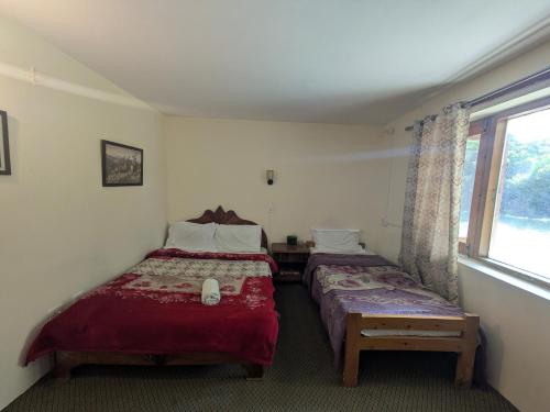 a bedroom with two beds and a window at White Apricot Lodge in Baltit