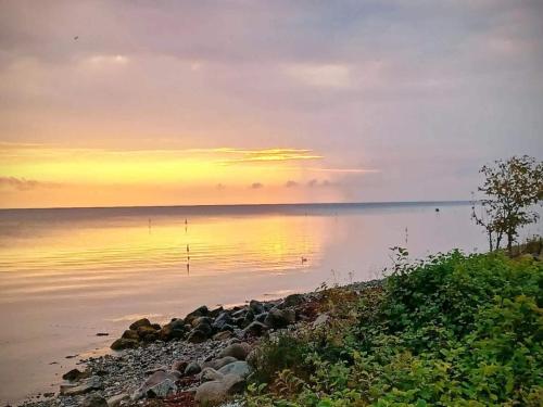 a sunset over a body of water with rocks at 3 person holiday home in Kerteminde-By Traum in Kerteminde
