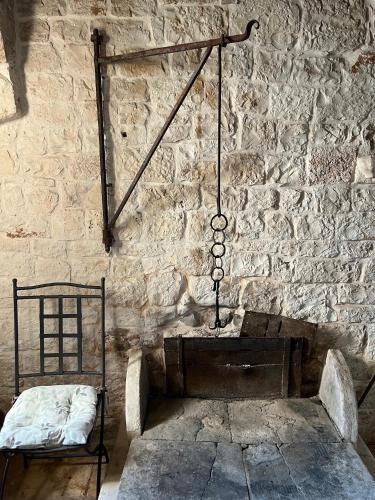 a room with a stone wall with a bed and a chair at CASINA 1806 Selva di Fasano in Selva di Fasano