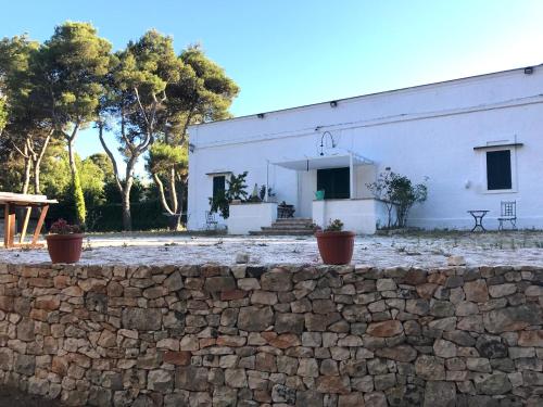 a white building with a stone wall in front of it at CASINA 1806 Selva di Fasano in Selva di Fasano