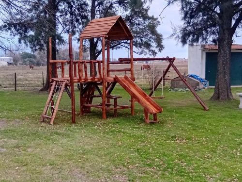 a wooden playground with a ladder and a swing at Hostel el Rincón in San Antonio de Areco
