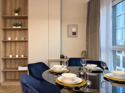 comedor con mesa de cristal y sillas azules en URBAN APARTMENTS GLOBAL SkyLine, 25th floor No 05, Free Garage, Self Check-in, No Deposit, en Katowice