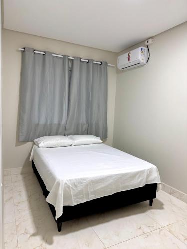 a bedroom with a bed with white sheets and a window at Casa espaçosa de férias in Foz do Iguaçu
