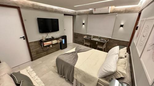 a bedroom with a bed and a tv and a table at Apartamento aconchegante na Serra de São Bento in Serra de São Bento