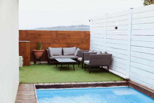 a patio with chairs and a table and a pool at mimar מימאר אירוח כפרי מפנק in Had Nes