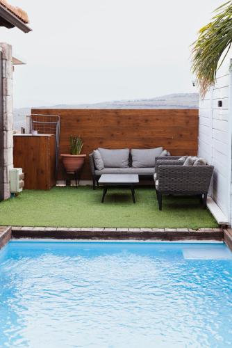 a backyard with a couch and a pool at mimar מימאר אירוח כפרי מפנק in Had Nes