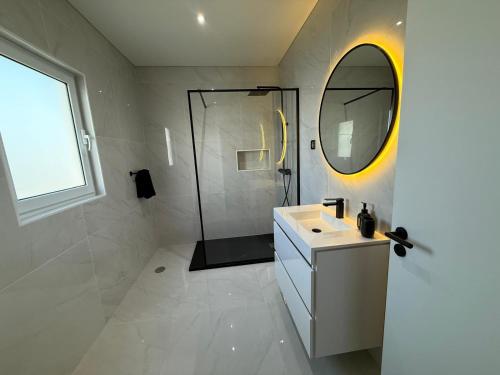 a bathroom with a sink and a mirror and a shower at The Frenchie's House in Rabo de Peixe