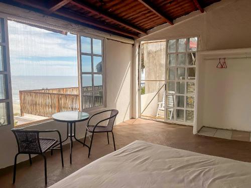 a bedroom with a table and chairs and a view of the ocean at Casa las Olas, vista al mar, surf y alberca in San Miguel del Puerto