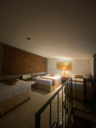 a bedroom with two beds and a brick wall at Hostal Fuente Castalia, B y B in León