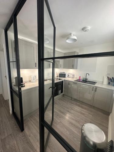 a kitchen with white cabinets and a glass door at House by the Sea, Worthing in Worthing