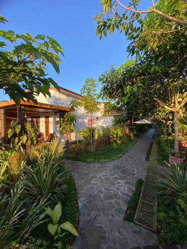 a pathway leading to a house with trees and plants at Tzy-No Cottage Yogyakarta in Balong