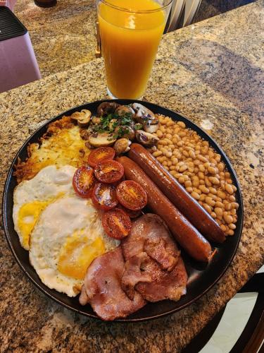 a plate of breakfast food with eggs sausage beans and a glass of juice at Silver Gates BnB in Mbabane