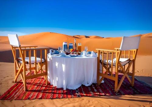 a table and two chairs in the desert at Sahary Tafilalt Luxury Camp in Merzouga