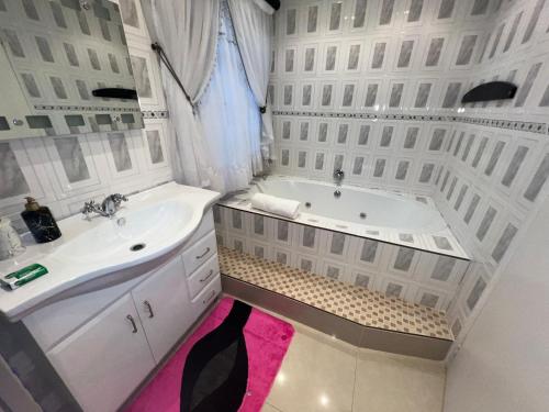 a white bathroom with a tub and a sink at Silver Gates BnB in Mbabane