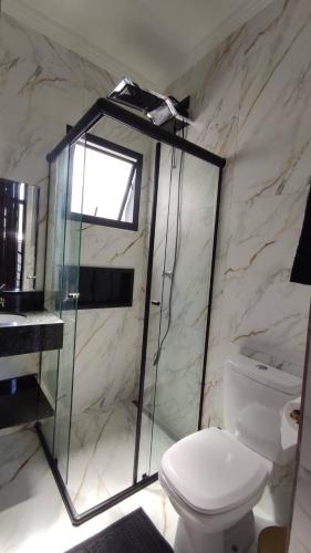 a bathroom with a glass shower and a toilet at Loft de luxo em Peruíbe, 3 minutos da praia in Peruíbe