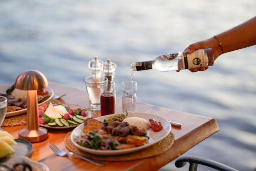 a person pouring wine into a plate of food on a table at Marimare Beach & Bungalow in Marmaris