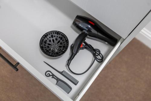 a black hairdryer and tools on a drawer at St James Court Aparthotel in Derby