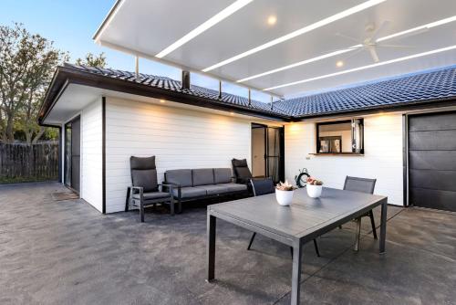 a patio with a table and a couch at Pipers Spot - Pet Friendly - Fireplace with Swimming Pool in Culburra Beach