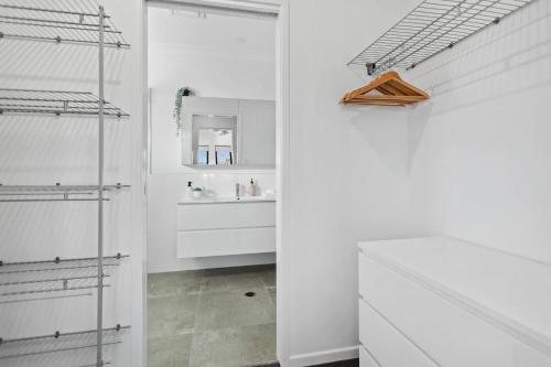 a white bathroom with a sink and a mirror at Trinity Oasis Spa BBQ & Family Retreat in Trinity Beach