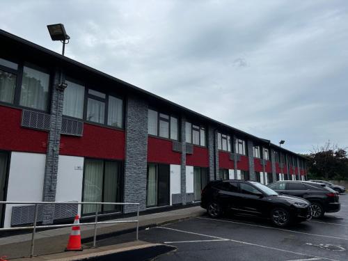 a black car parked in a parking lot next to a building at Ramada by Wyndham Kingston in Kingston