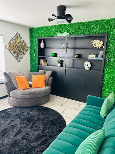 a living room with a couch and a green wall at The Greenhouse Effect in Corpus Christi